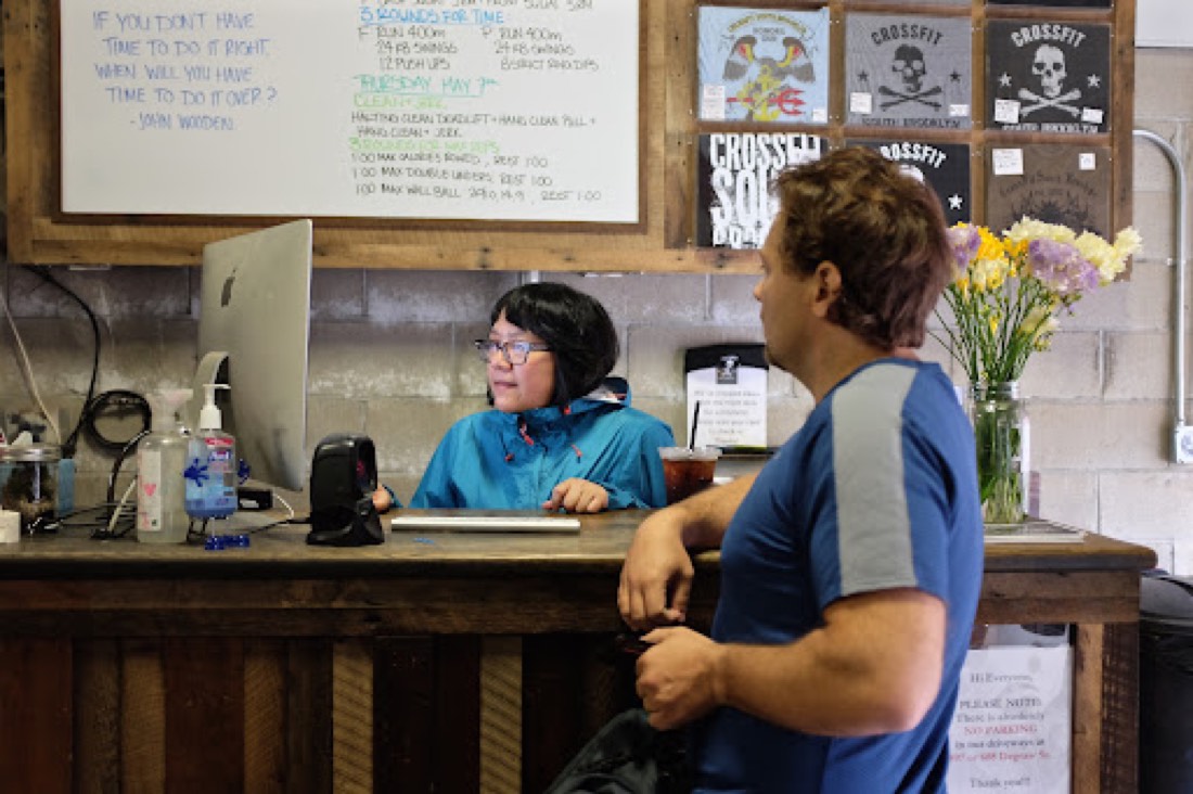 Gym staff helping a member at the front desk on a computer